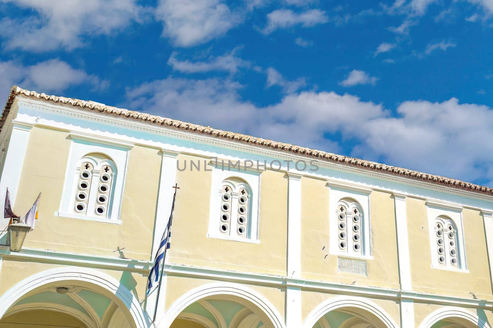 St. George Holy Orthodox Metropolitan Christian Church against a blue sky with clouds in Nafplion, Greece.