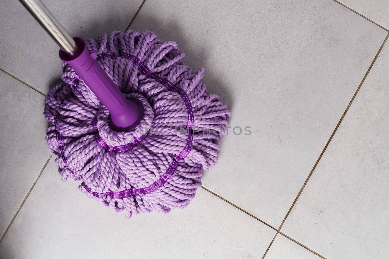 Purple mop on the bathroom floor. The concept of indoor cleaning. copy space.