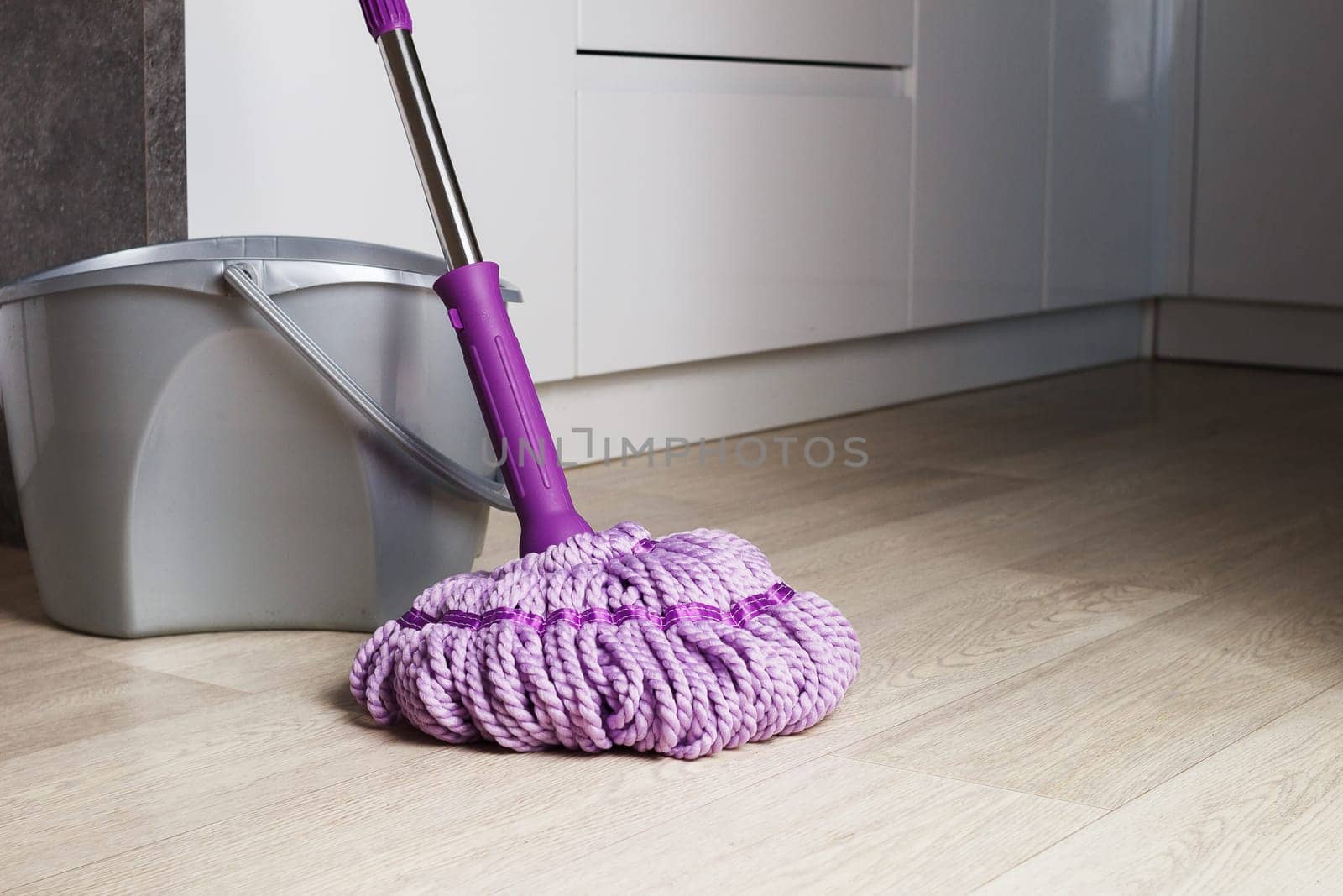 Purple mop on the bathroom floor. The concept of indoor cleaning. copy space.