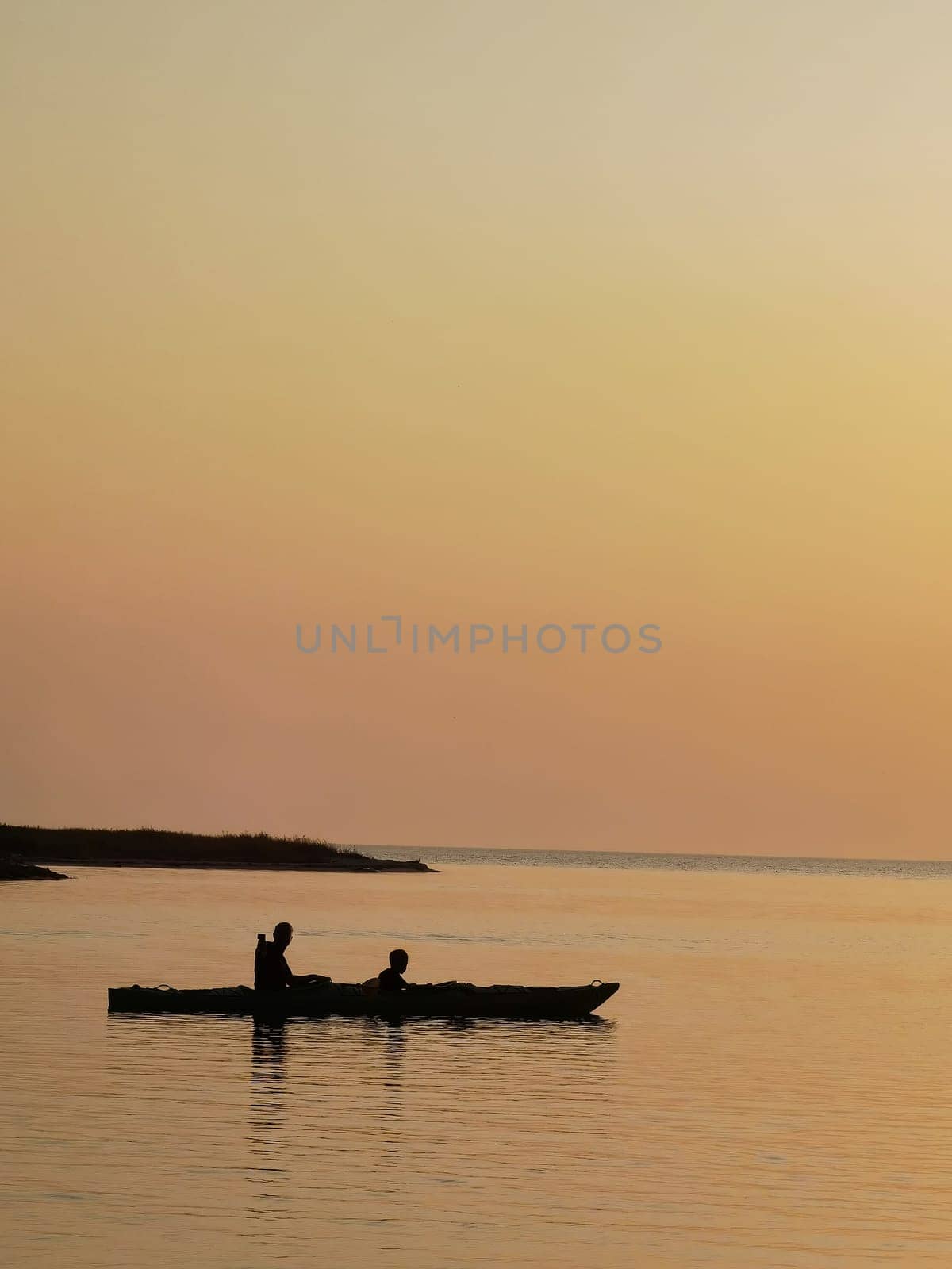 silhouette of a couple on a boat in the sea at sunset.