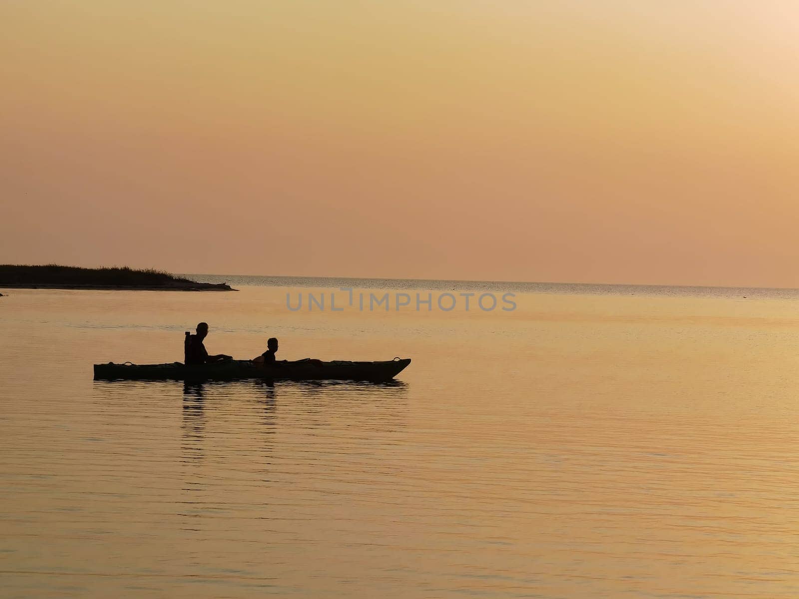 silhouette of a couple on a boat in the sea at sunset by sarymsakov