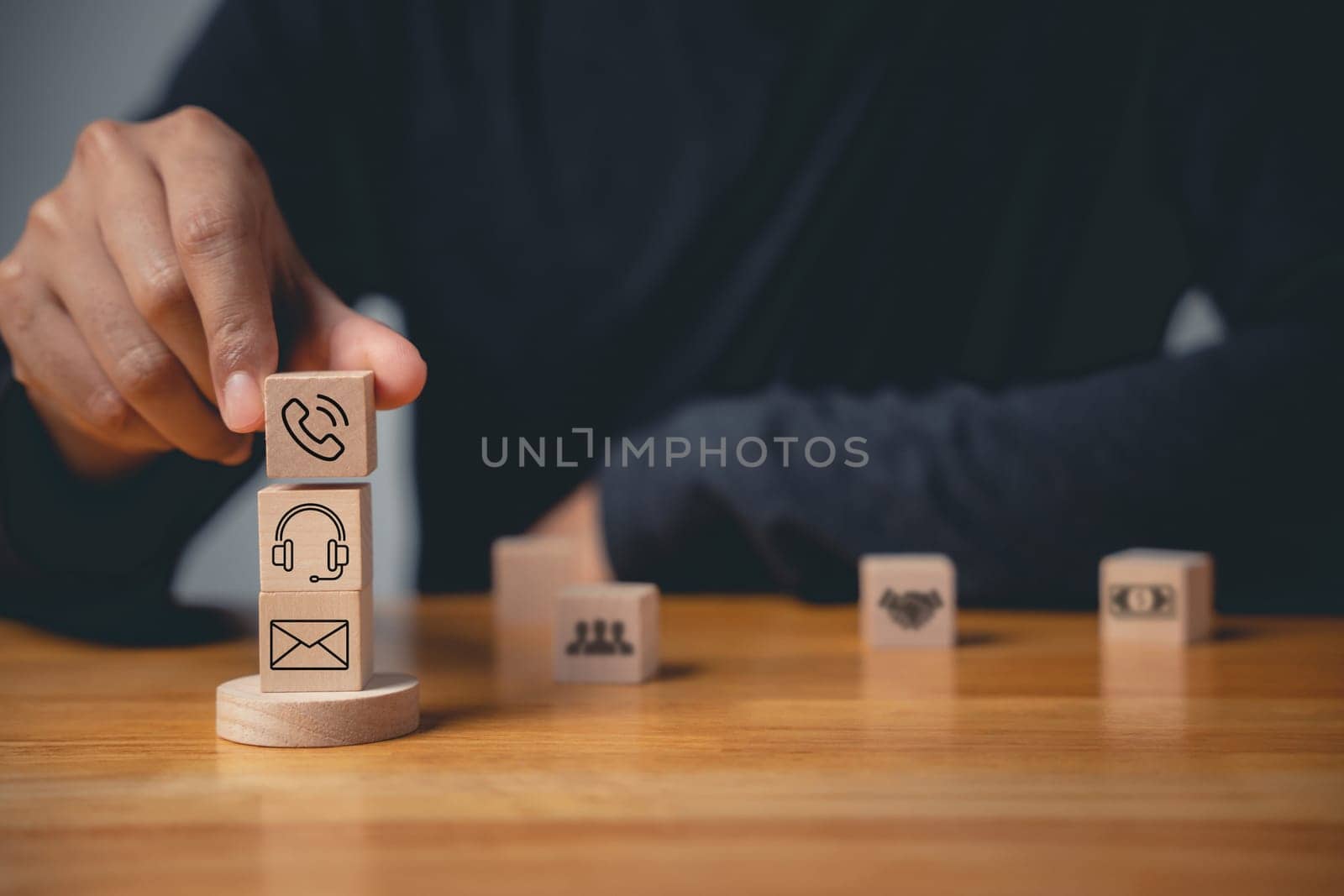 Contact us or e-mail marketing concept on website page. Customer support hotline connects people. Wood cube with email, phone, address, and headset icons. Symbolizes communication.