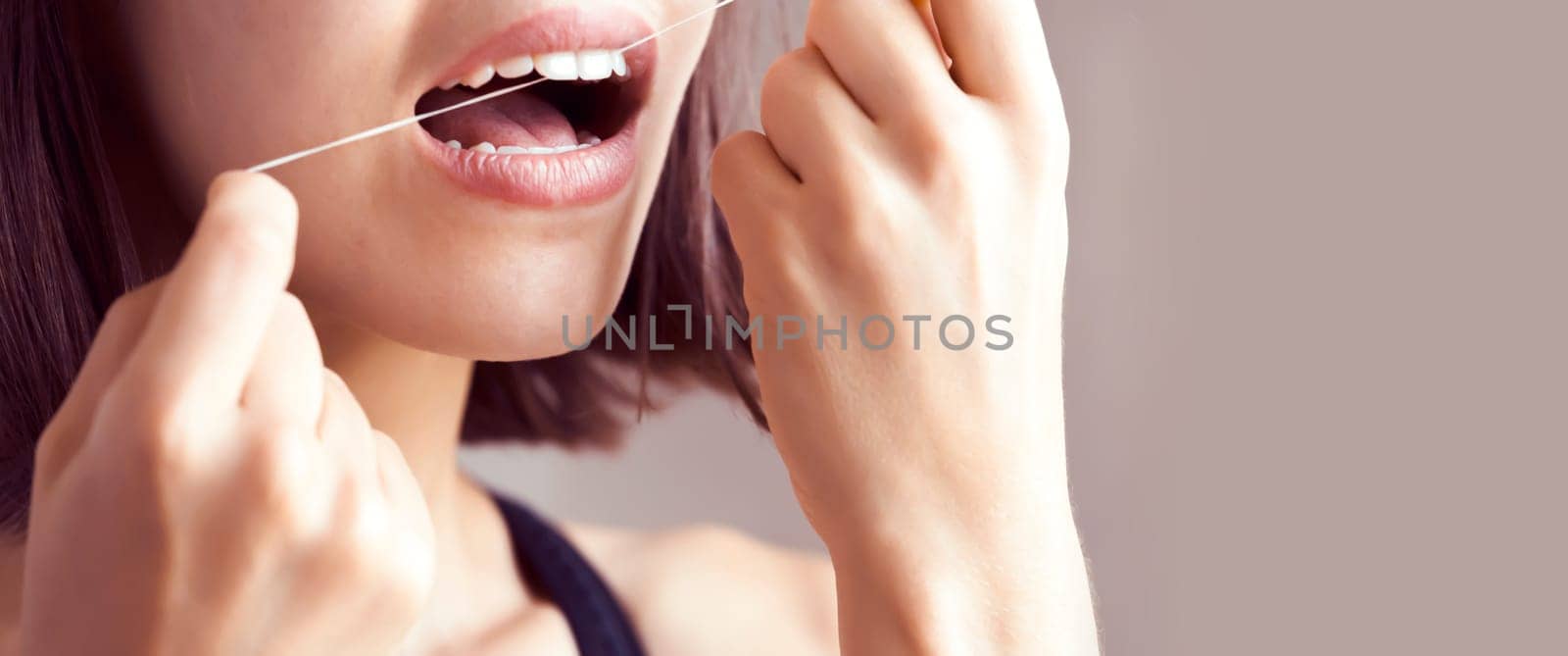 A young girl flosses her teeth, a woman takes good care of her snow-white smile, the health of her gums and tooth enamel.