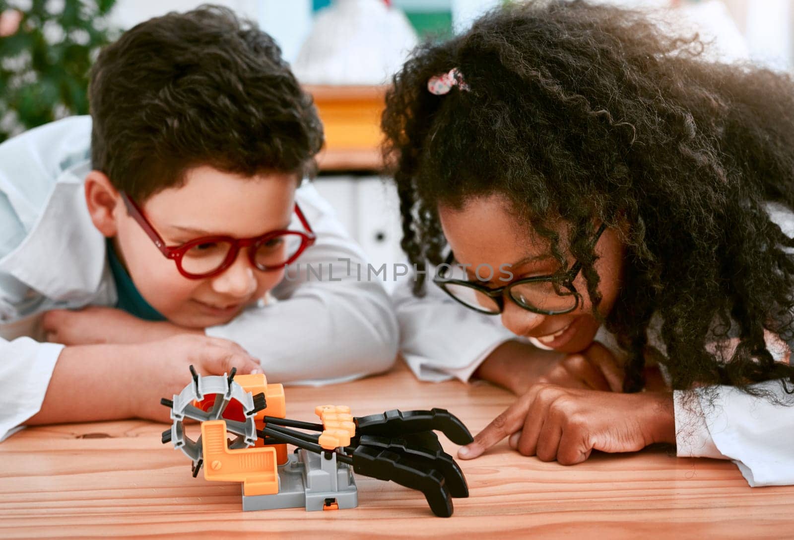 Engineering, learning and children building a robot hand together in a classroom at school and being curious. Clever, education and young engineer students working in a science class doing research.