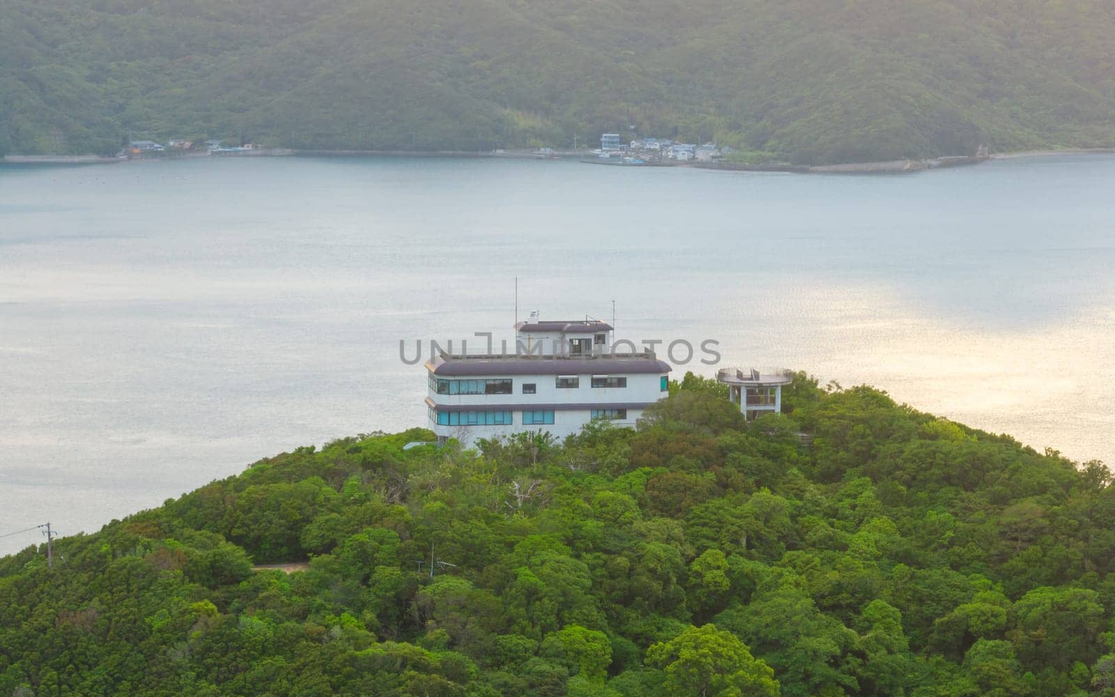 Remote house compound on forested hilltop on coast at golden hour. High quality photo