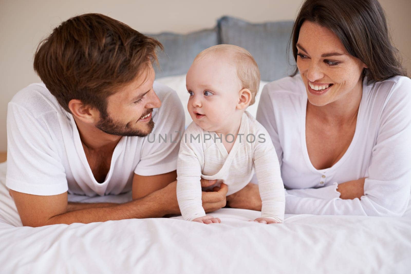 Happy family, dad and mom with baby on bed for love, care and quality time together at home. Mother, father and cute newborn child relaxing in bedroom for happiness, support and development of kids by YuriArcurs