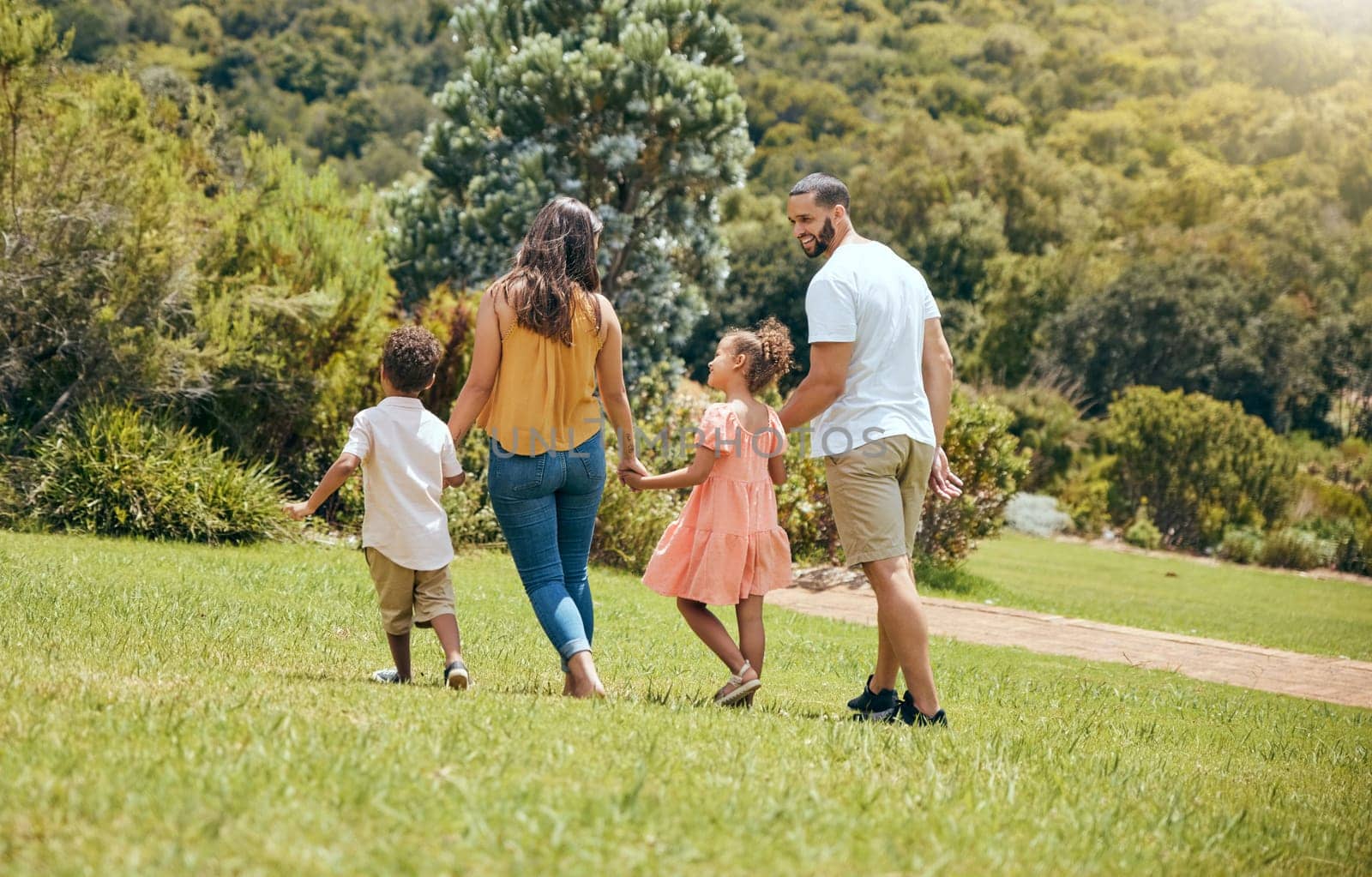 Family, kids and walking in the park for bonding, fun and care in summer outside. Mother, father and parents playfully walk with children, son and daughter siblings in a garden for bond.