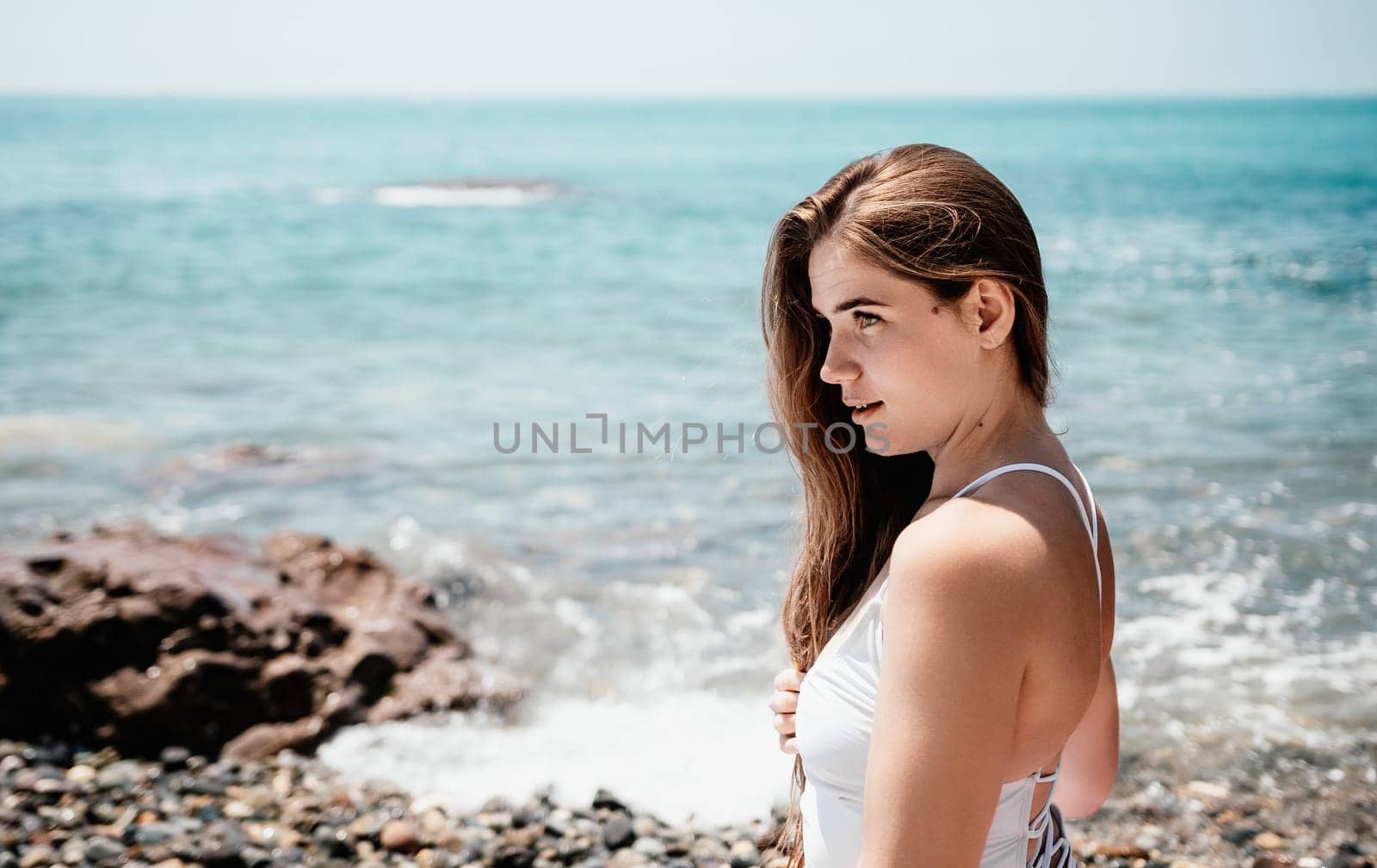 Young woman with black hair, fitness instructor in pink sports leggings and tops, doing pilates on yoga mat with magic pilates ring by the sea on the beach. Female fitness daily yoga concept