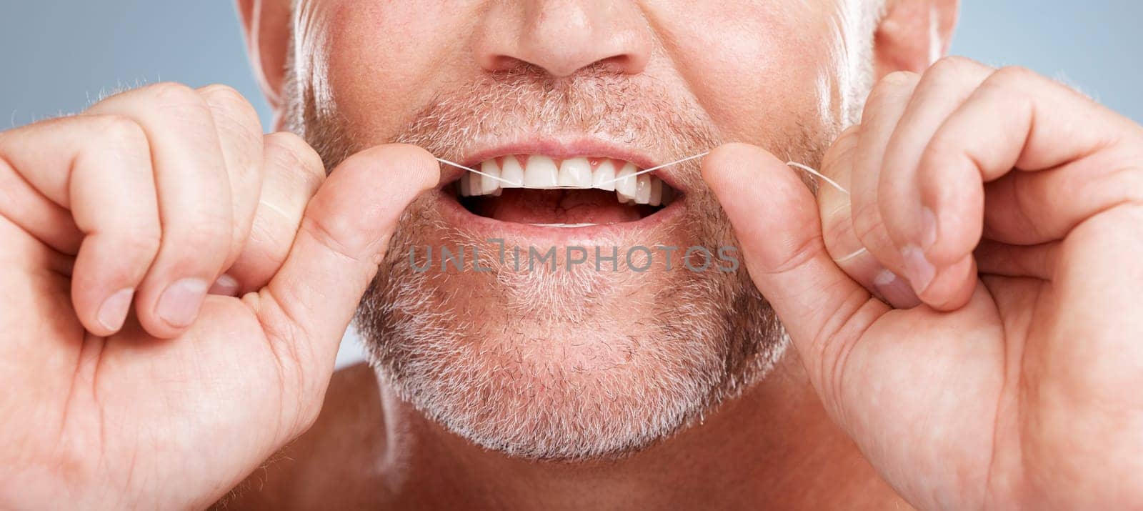 Closeup, floss and man with dental health, cleaning teeth and fresh breath against grey studio background. Male, gentleman and string for oral hygiene, wellness and morning routine for mouth grooming by YuriArcurs