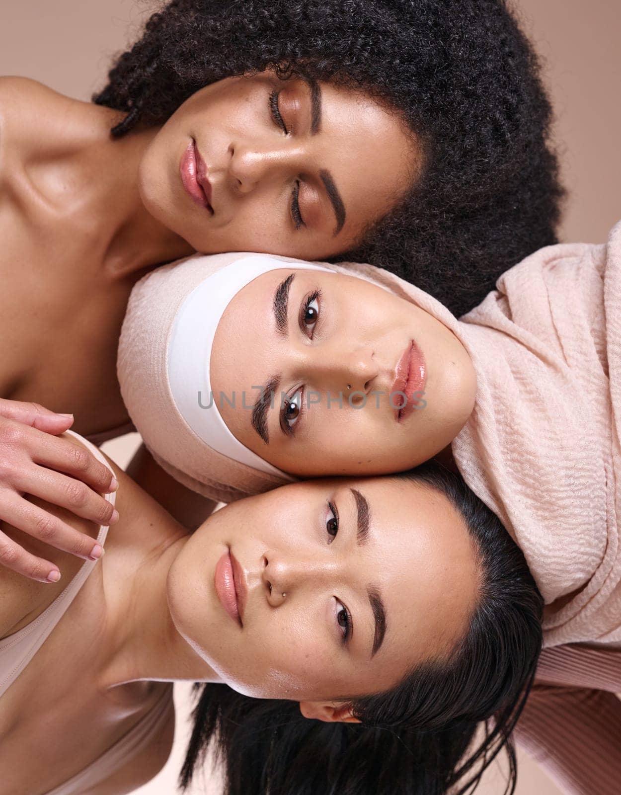 Portrait, beauty and diversity with woman friends in studio on a brown background for skincare or inclusion. Face, pile and natural with a model female friend group posing to promote equality by YuriArcurs