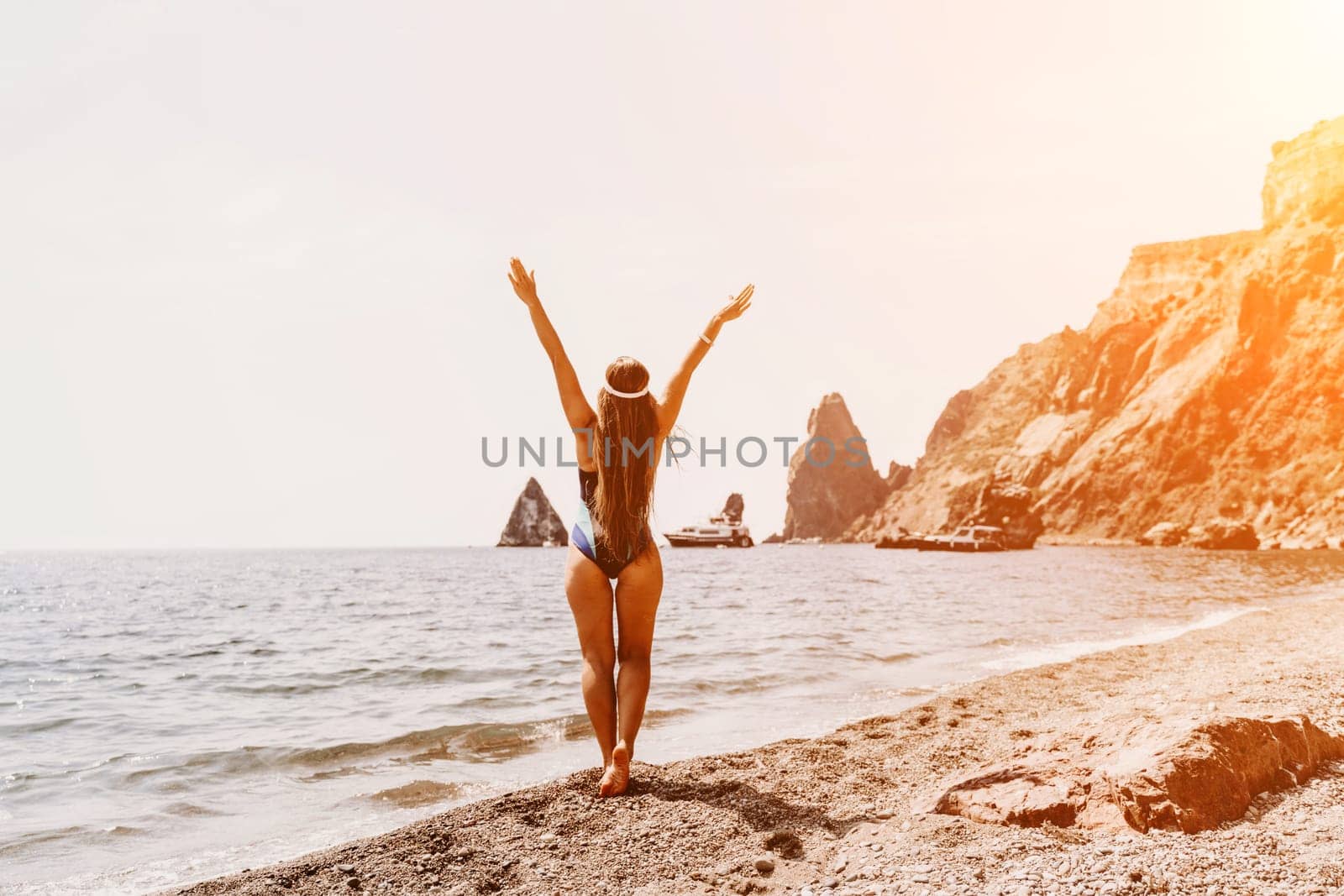 Woman beach vacation photo. A happy tourist in a blue bikini enjoying the scenic view of the sea and volcanic mountains while taking pictures to capture the memories of her travel adventure. by Matiunina