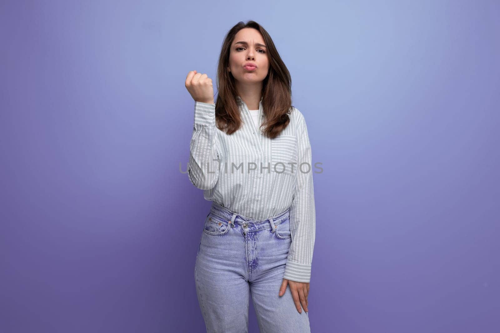 energetic emotional young brunette female adult in a striped shirt and jeans on a studio background by TRMK