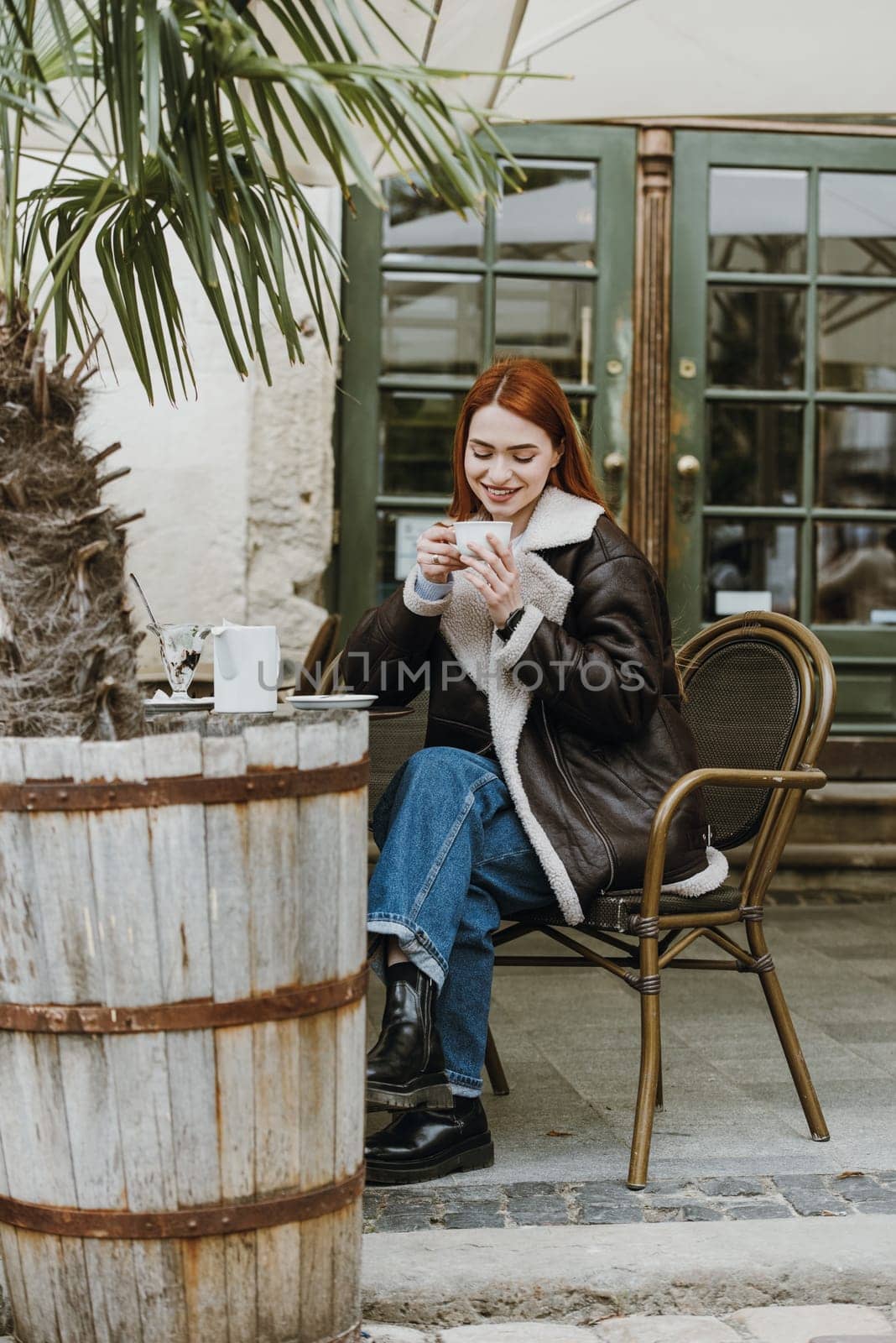 a red-haired girl in a leather jacket. great morning with coffee on the summer terrace in the cafe