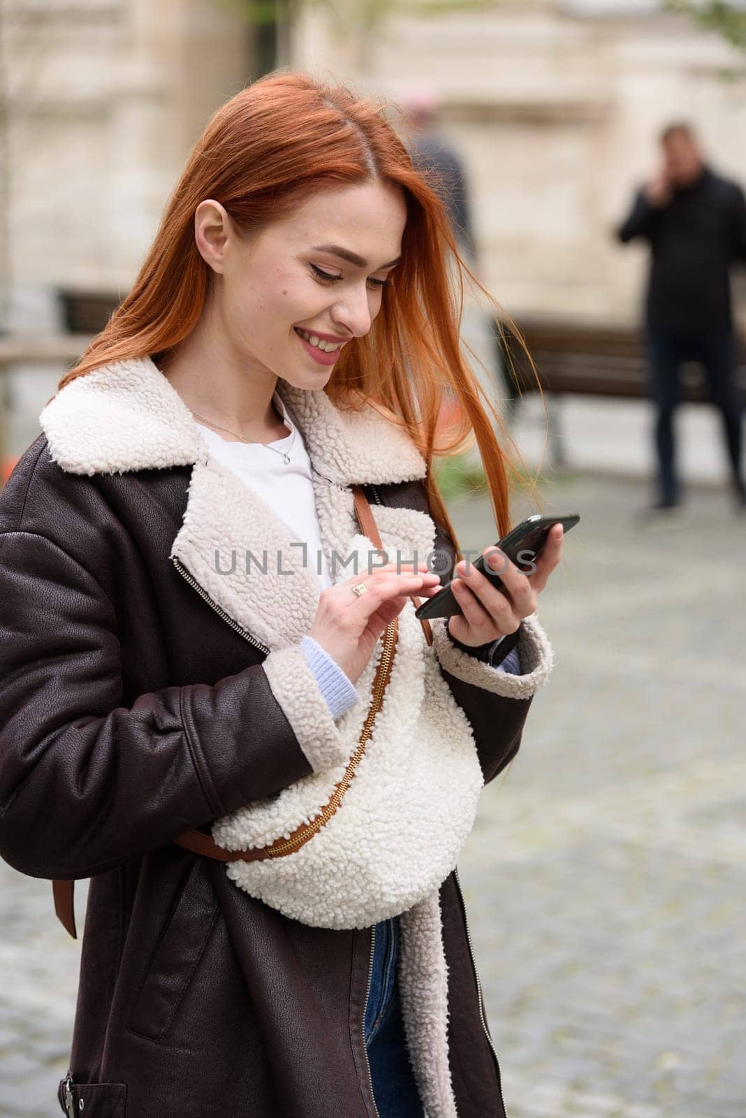 happy woman communicates with friends via video link outdoors on an old town street by Ashtray25