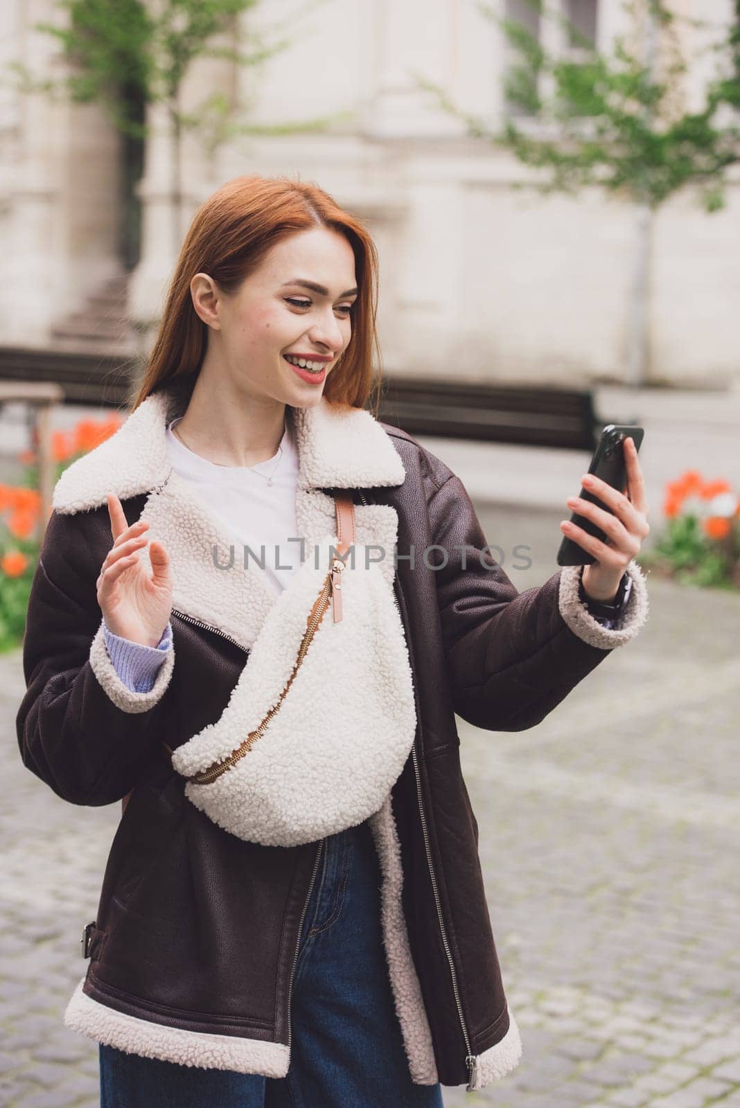 happy woman communicates with friends via video link outdoors on an old town street by Ashtray25