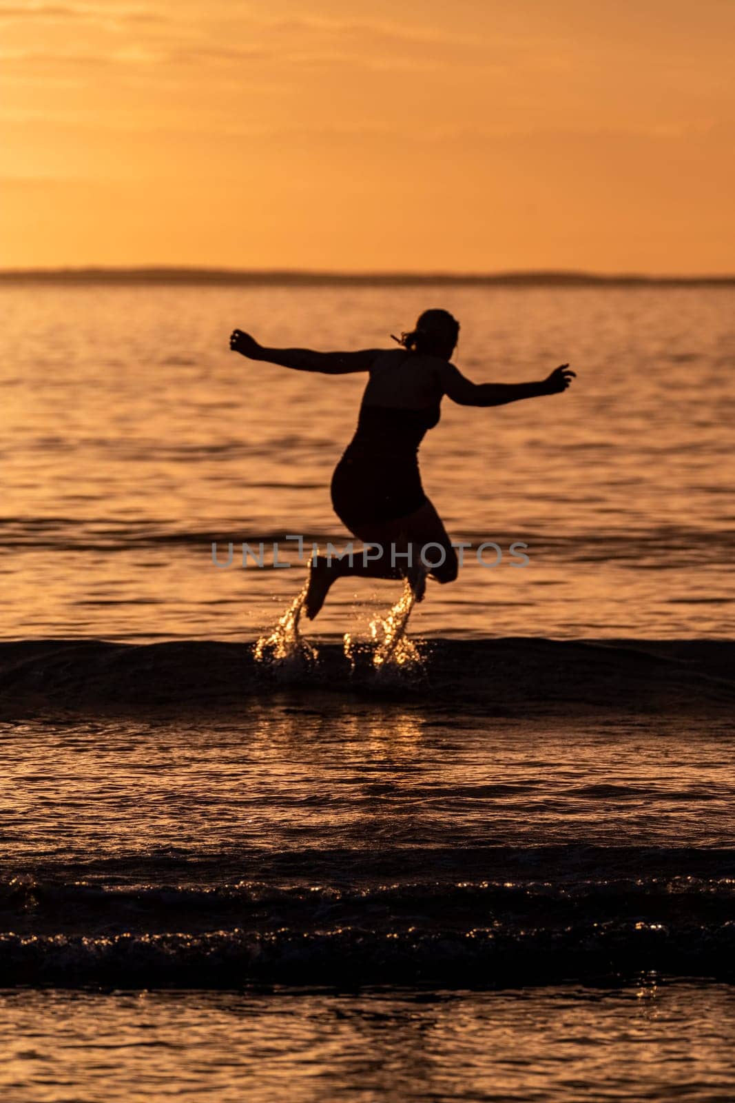 Silhouette of female swimmer having a splash in the Atlantic ocean in Ireland by TLC_Automation