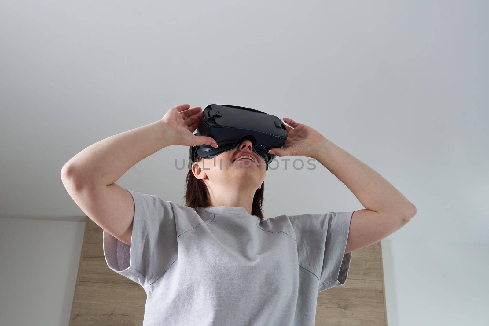 Happy young woman playing on VR glasses indoor. Virtual reality concept with young girl having fun with headset goggles.
