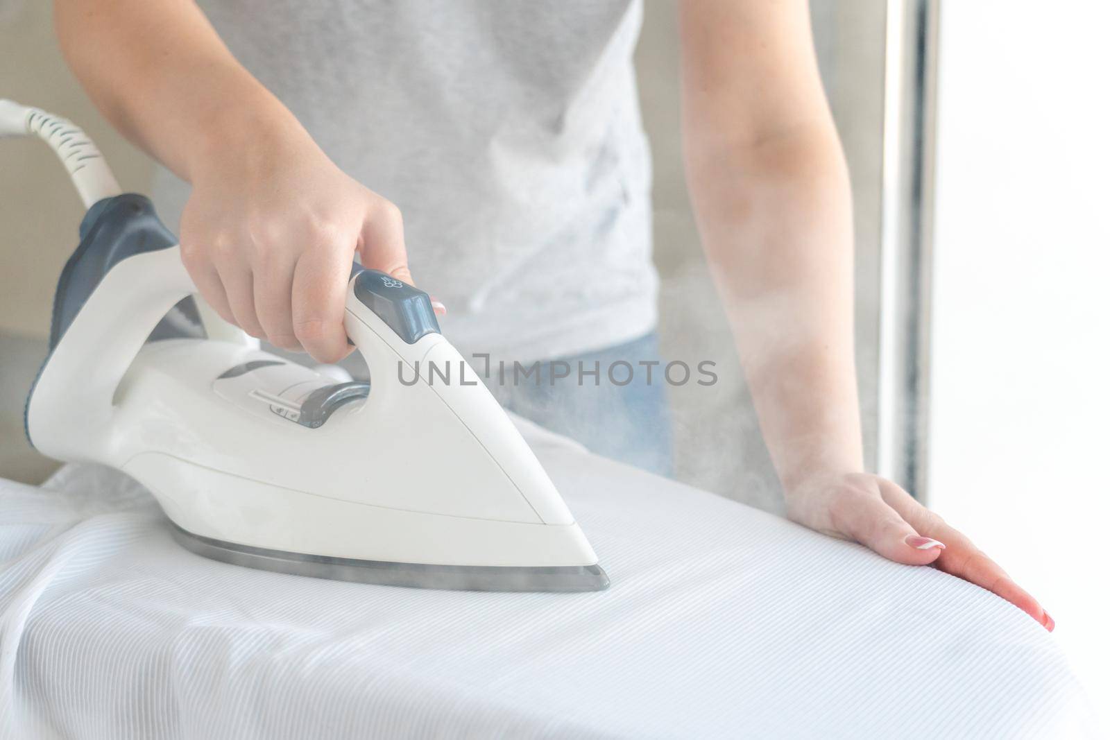 Close up of Female hands ironing white shirt on ironing board