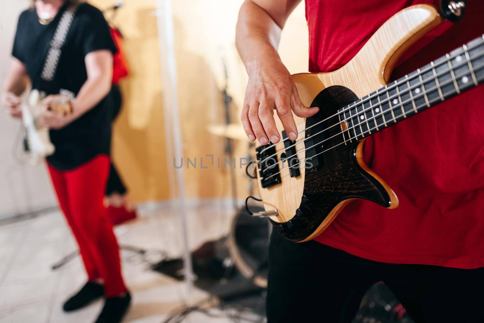 Rock band studio rehearsal. Male musician playing bass guitar before concert
