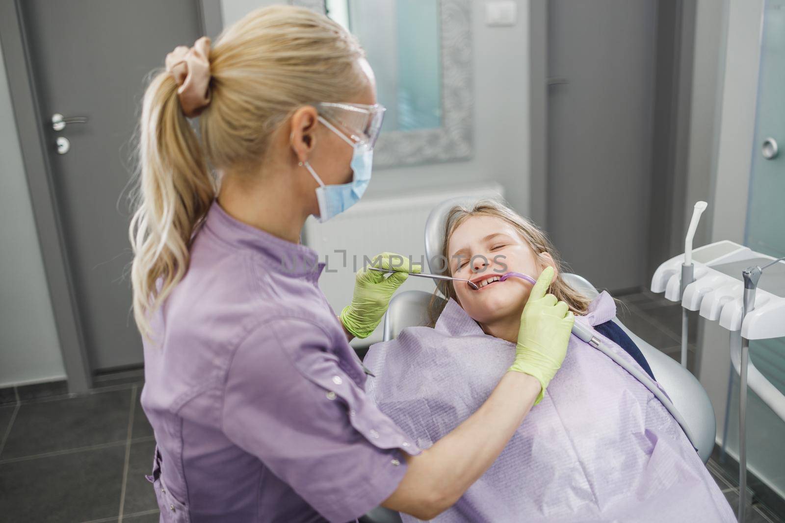 A female dentist examining cute little girl's teeth during dental procedure at dentist's office.