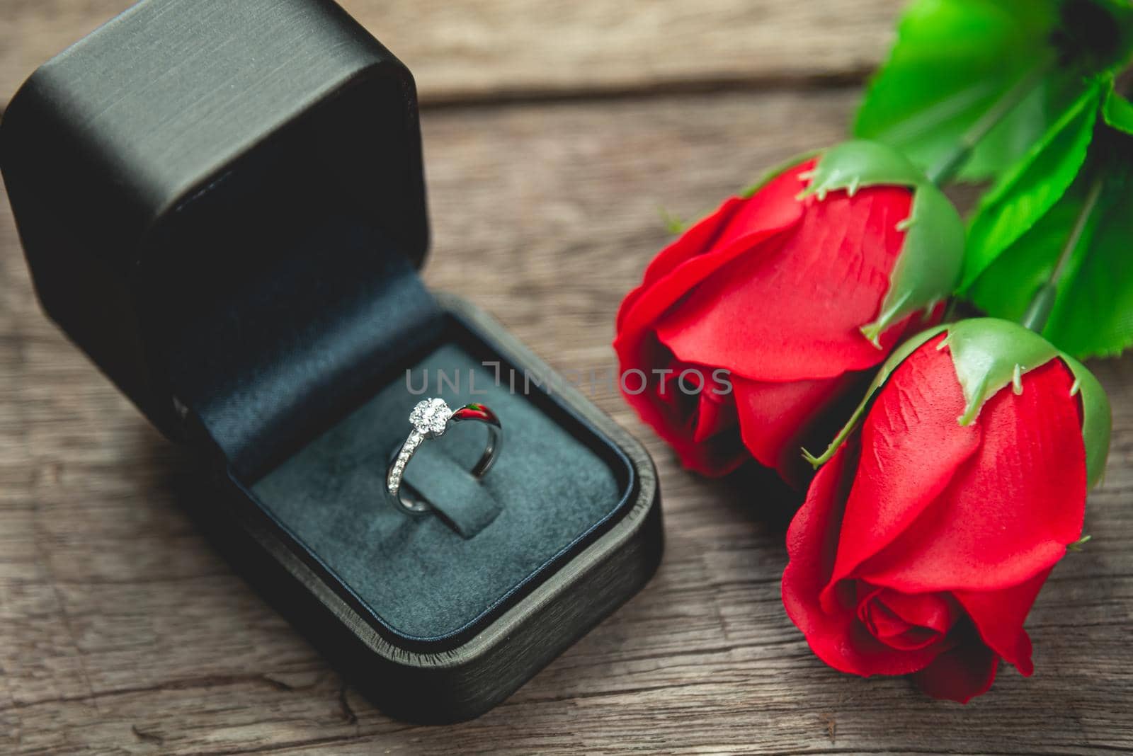 wedding ring and red rose flowers on wood table