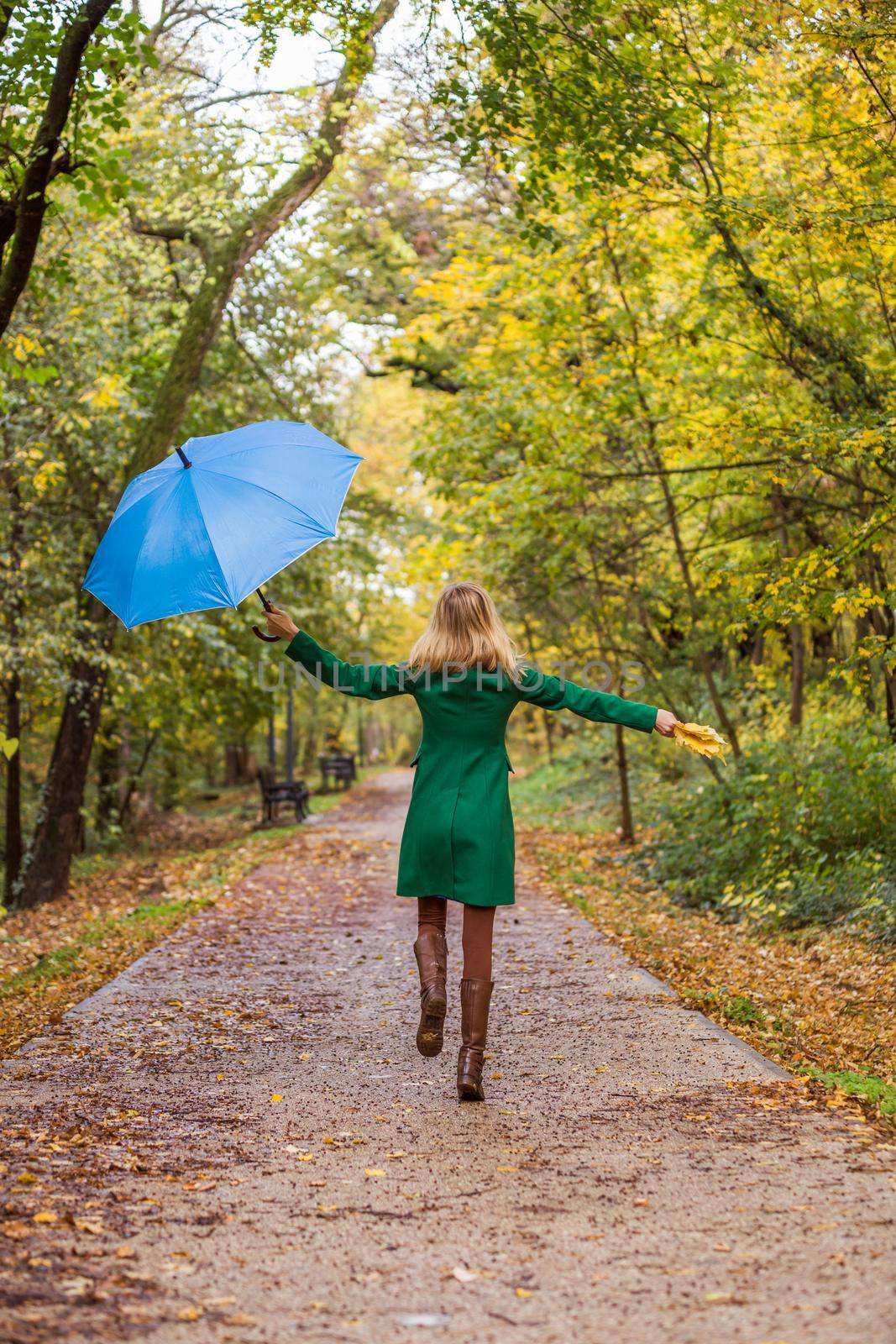 Woman holding umbrella and fall  leaves  while jumping and  walking in the park.