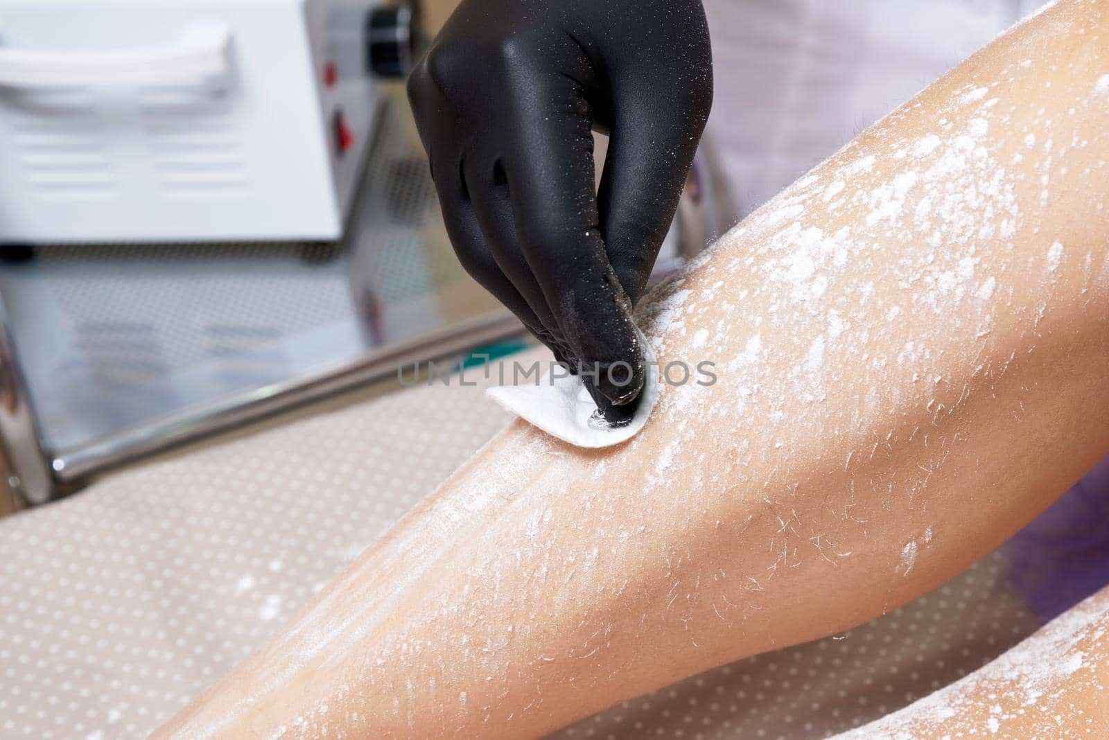 Beautician getting ready to wax female legs in spa center