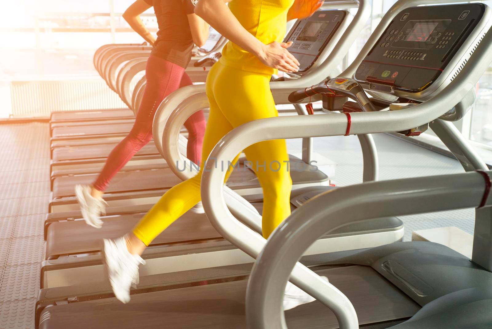 Two young women running on treadmill in a gym