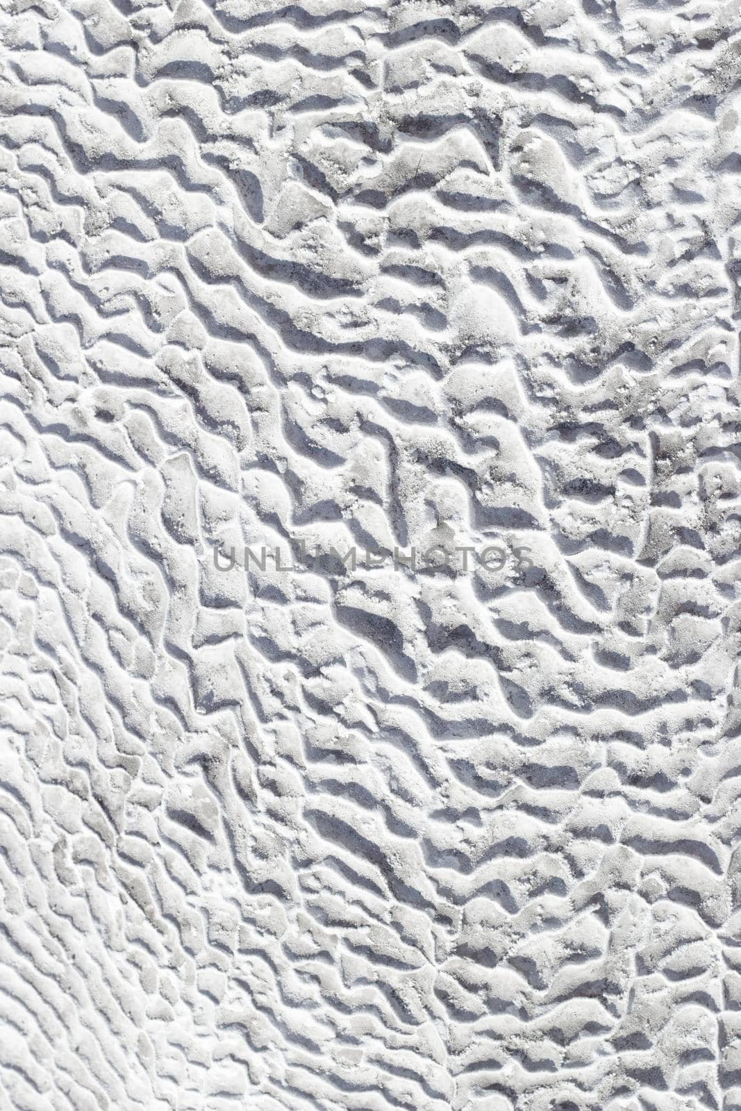 Gray-white texture of Pamukkale calcium travertine in Turkey, uneven pattern of cells close-up