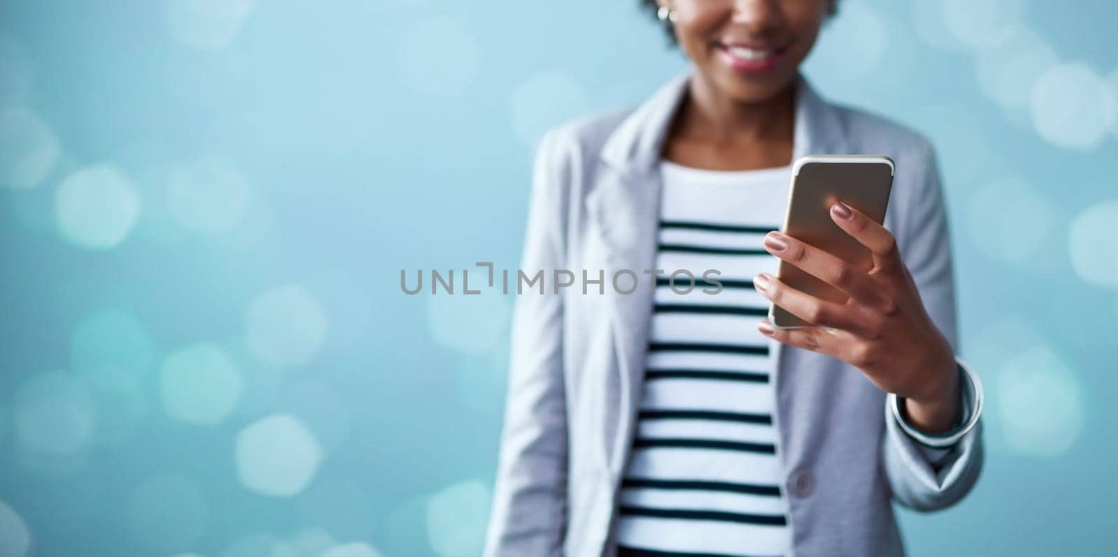 Cropped studio shot of a young businesswoman using a mobile phone against a blue background.