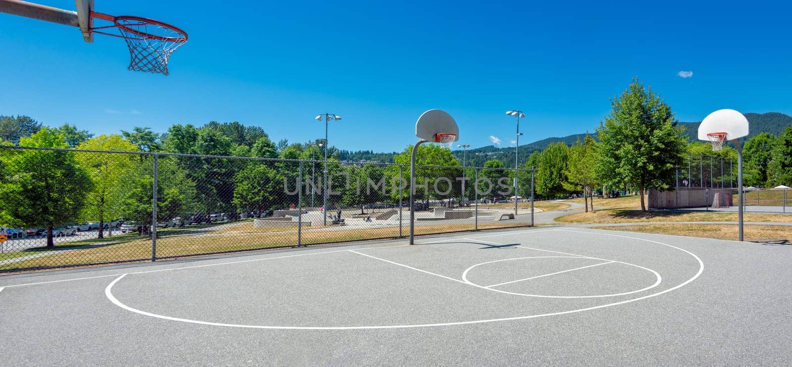 Playground with basketball court in a park on a bright sunny day by Imagenet