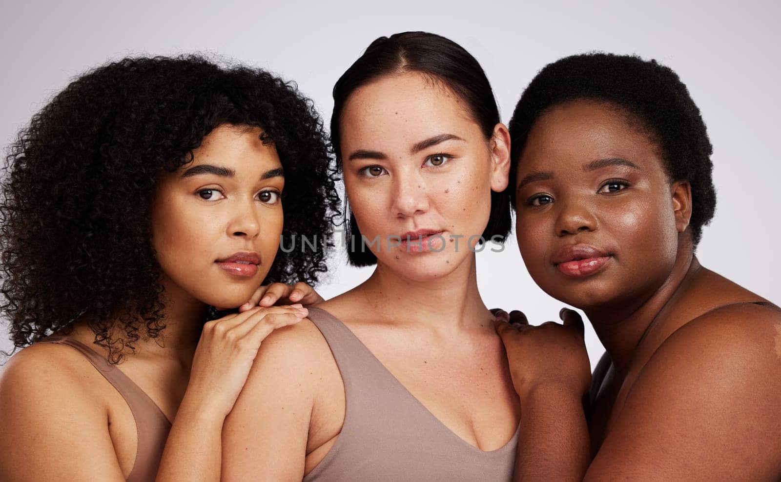 Portrait, beauty and diversity with woman friends in studio on a gray background together for skincare. Face, makeup and natural with a female model group posing to promote support or inclusion.