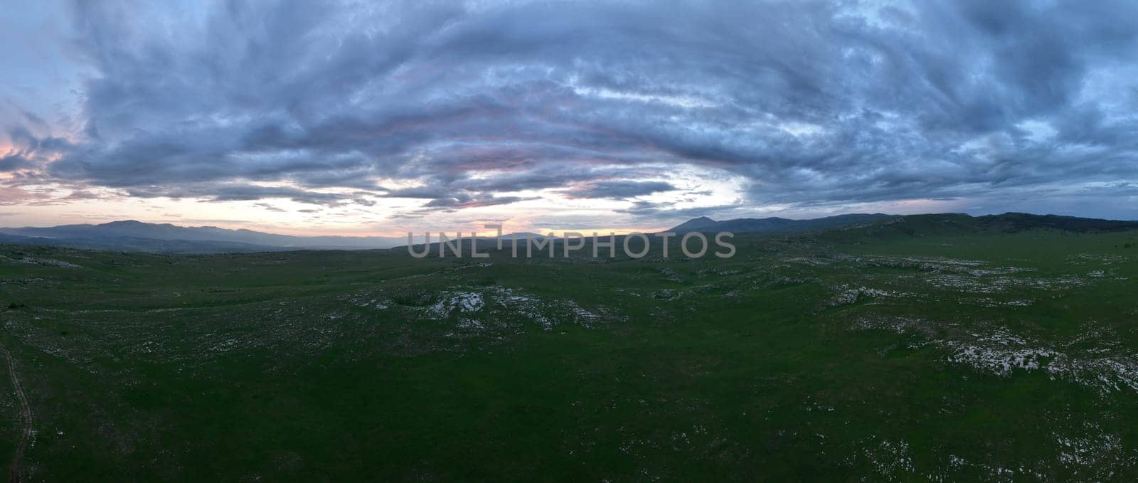 Aerial view of countryside landscape. Clouds with shades of purple, orange and green vegetation. Dramatic sky. High quality stock photo