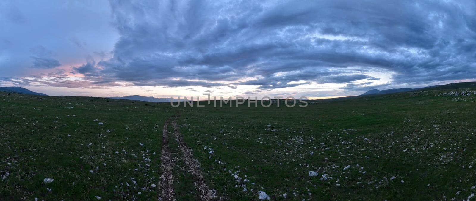 Aerial view of countryside landscape. Clouds with shades of purple, orange and green vegetation. Dramatic sky. High quality stock photo