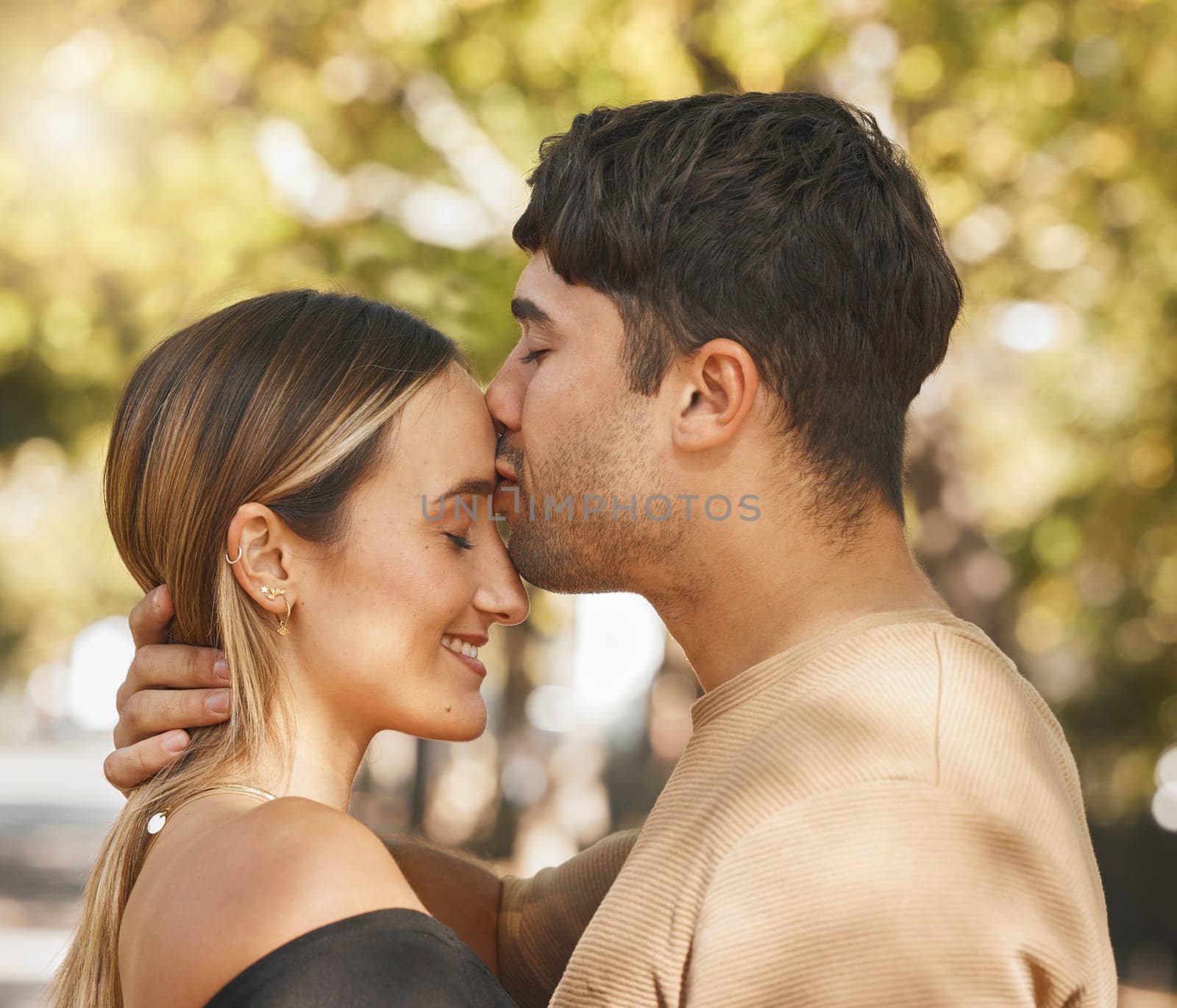 Kiss, love and romance with a couple bonding outdoor during a date on a summer day. Happy, trust and smile with a young man and woman kissing outside together while dating or being romantic by YuriArcurs