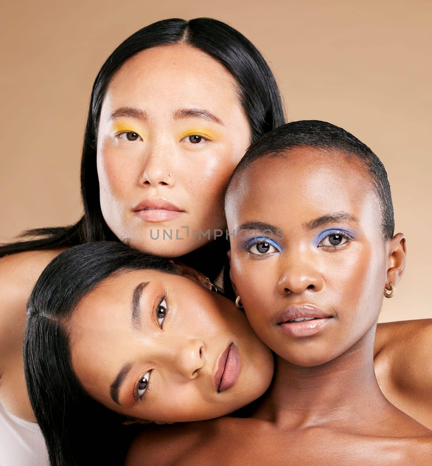 Diversity, woman and focus face with makeup, skincare beauty and cosmetics dermatology in brown background studio. Interracial models, facial care and support together for natural glowing skin.