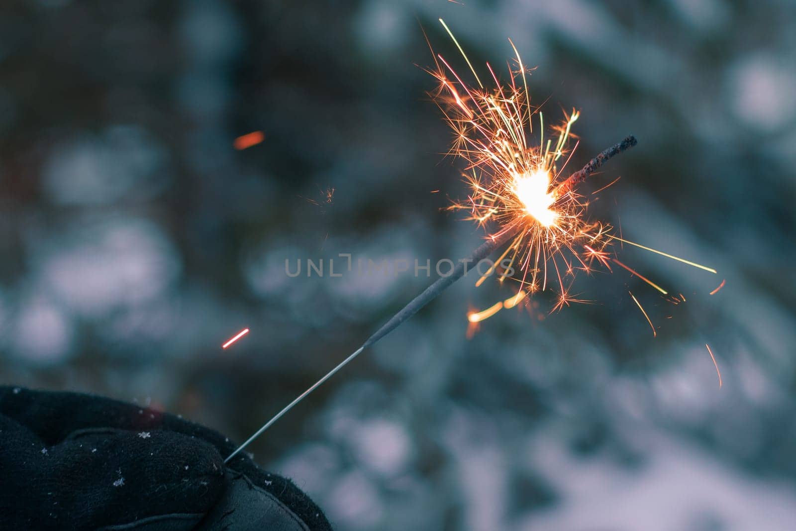 Burning Sparklers in a Hand Outdoors in Winter in Evening. New Year Celebration Party
