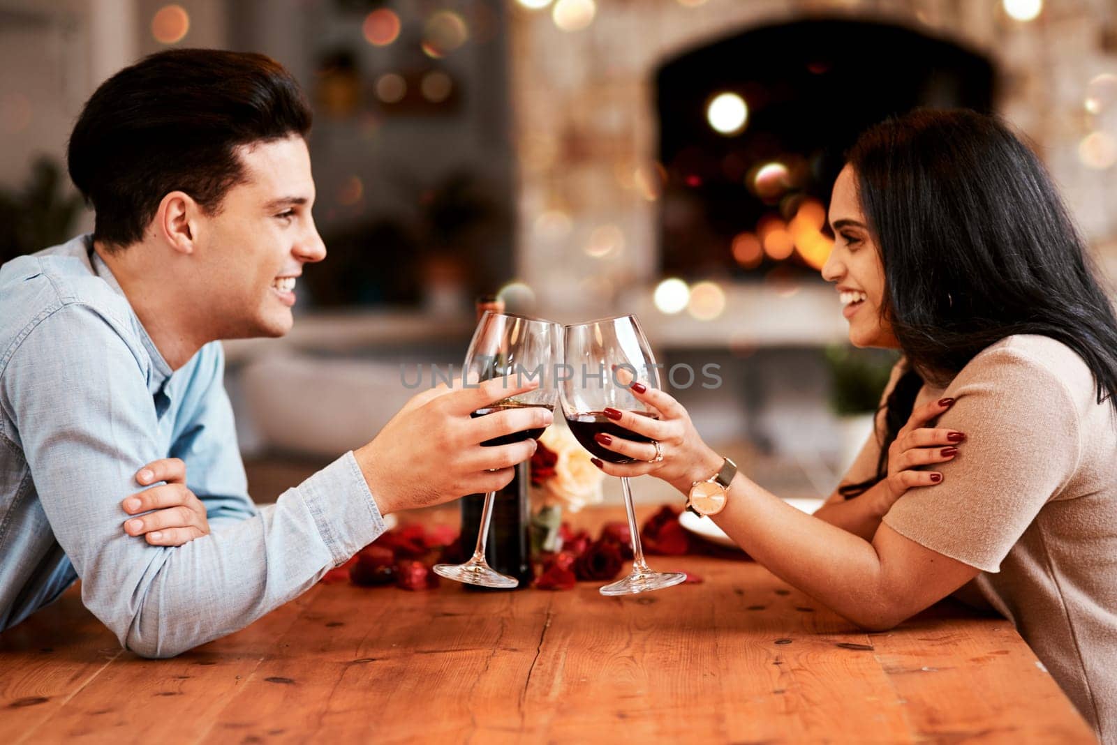 Love, wine and couple cheers on valentines day date at home with smile, romance and bokeh. Date night, man and woman at table in living room, valentine celebration and happy relationship together. by YuriArcurs