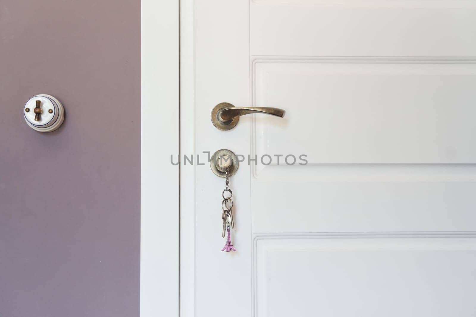 Part of white modern interior door with key in lock and metal handle by driver-s