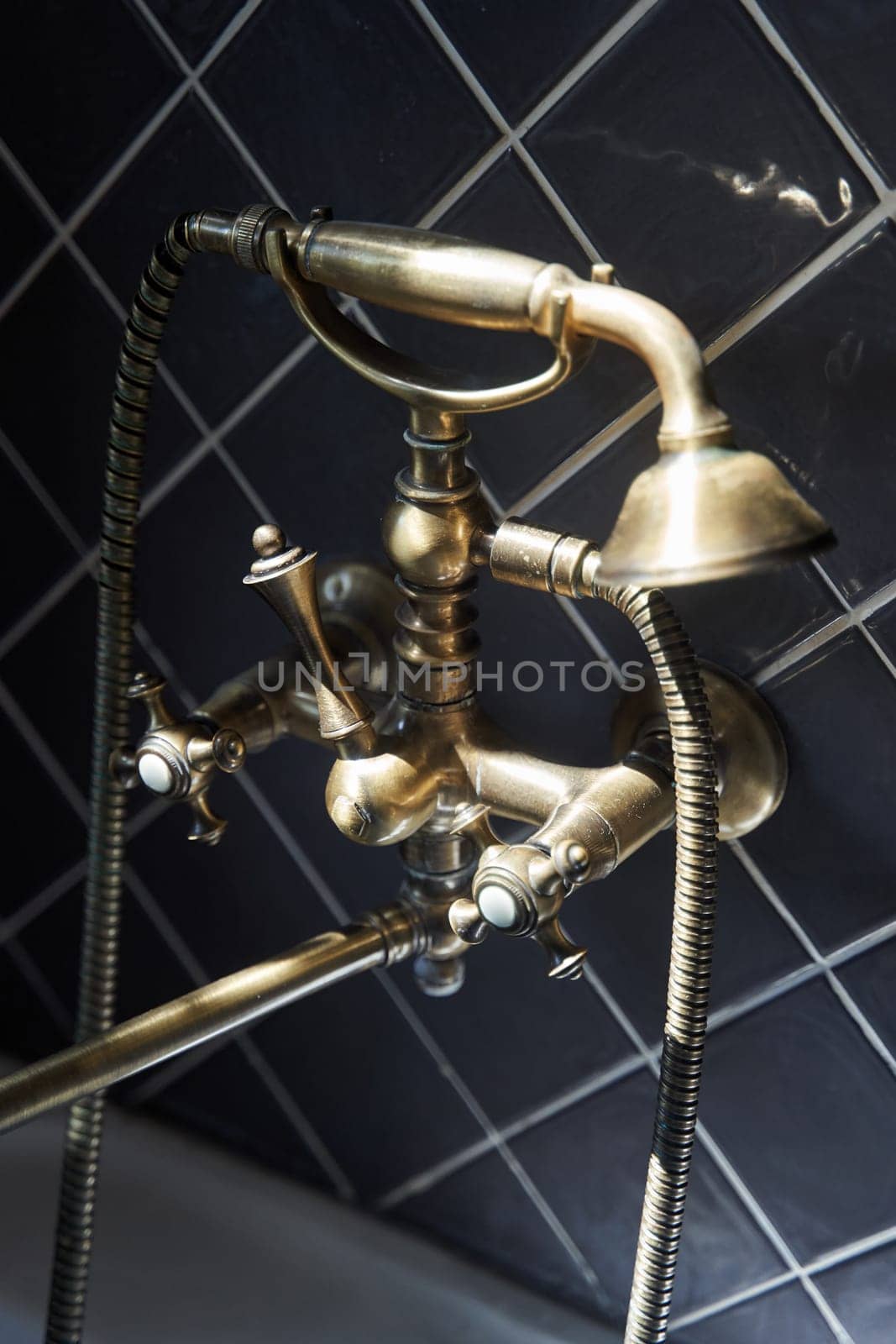 Gold faucet and shower old vintage style with grey tiles background. High quality photo