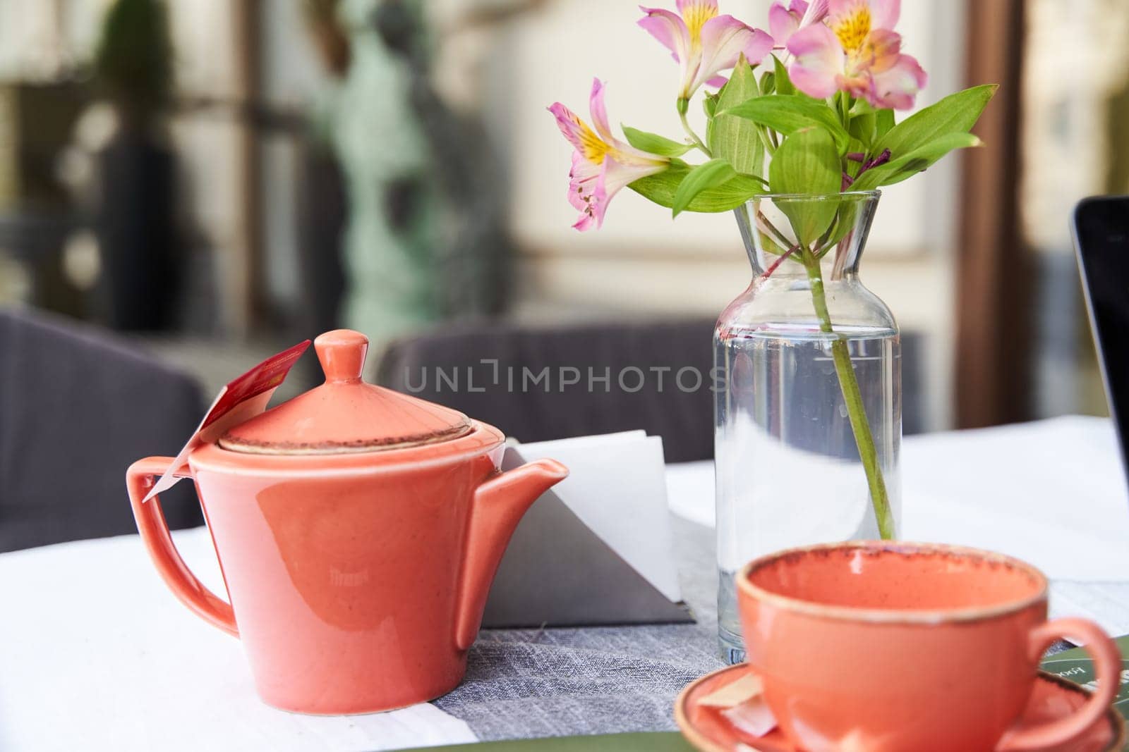 Tbilisi, Georgia - 22.04.2021: Flowers in a vase, a teapot and a cup on the table in a summer outdoor cafe by driver-s