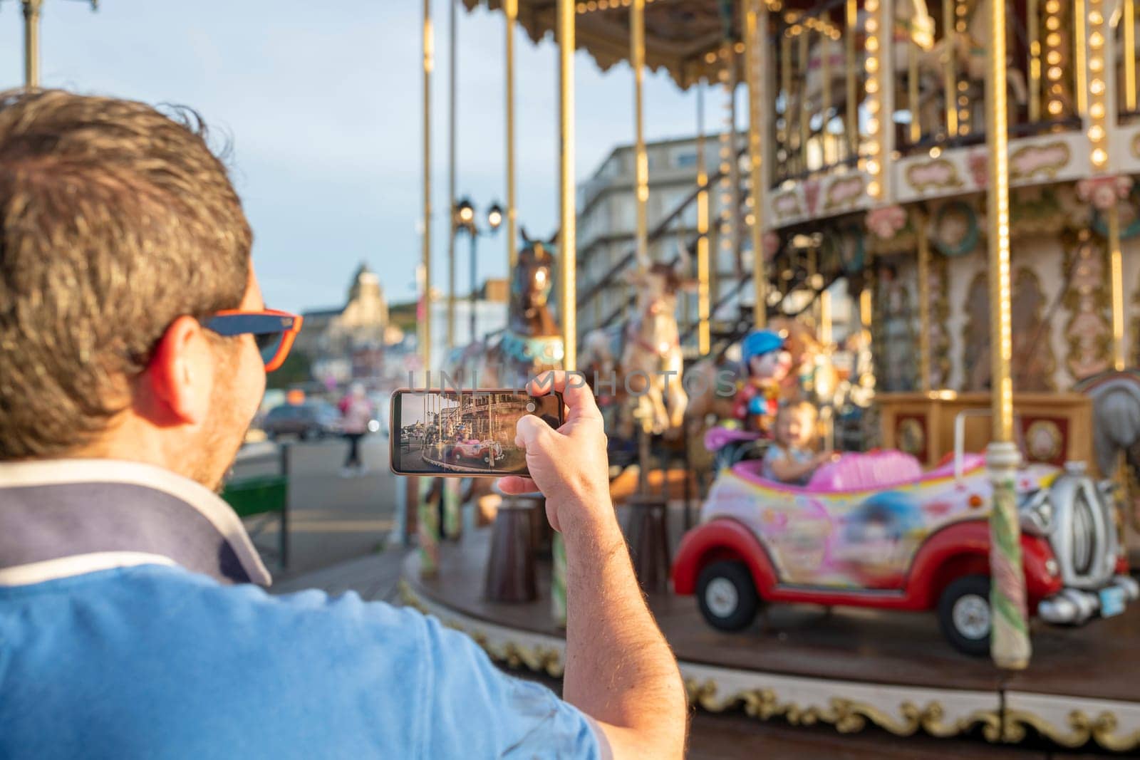 Father takes photos and videos of his daughter on the carousel on the phone
