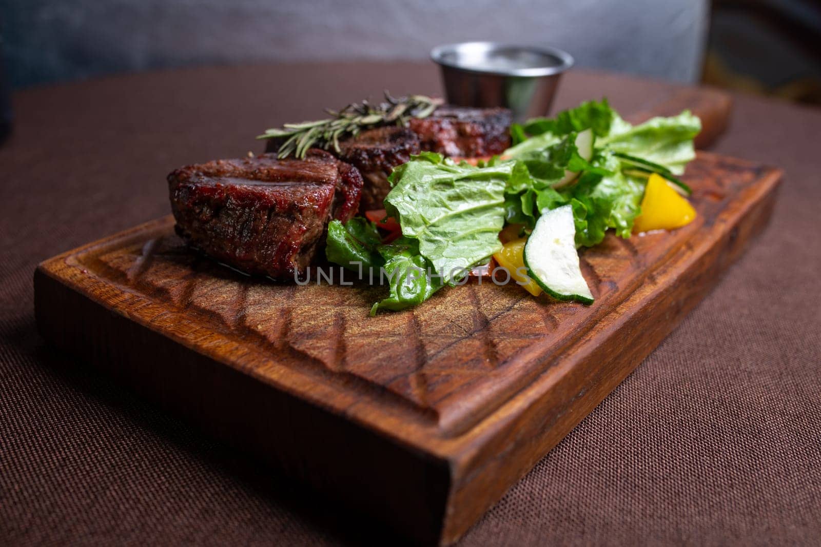 juicy beef steak with herbs and sauce on a wooden board by Pukhovskiy