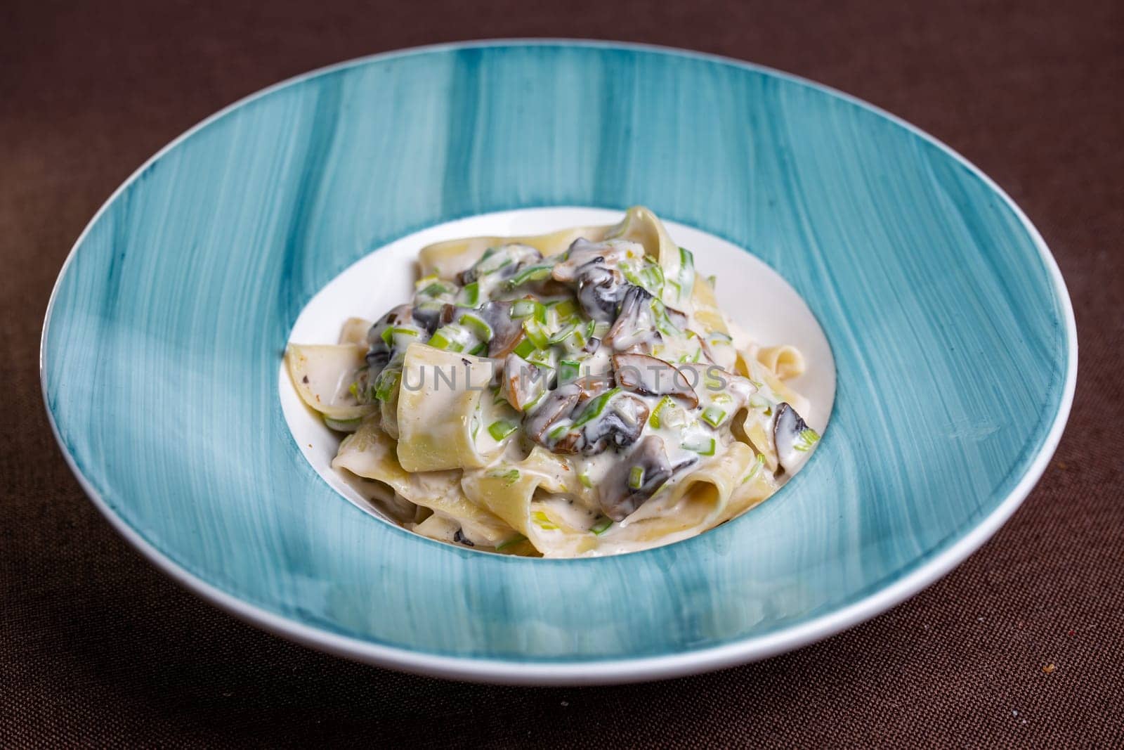 pasta with mushrooms and sauce in a blue plate.