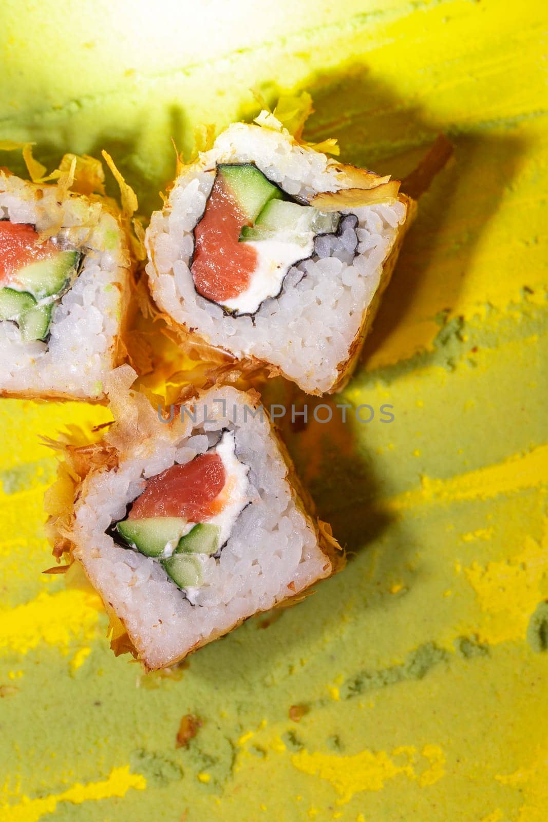 top view of Japanese cuisine rolls with fish, cucumber and cheese on a yellow background by Pukhovskiy