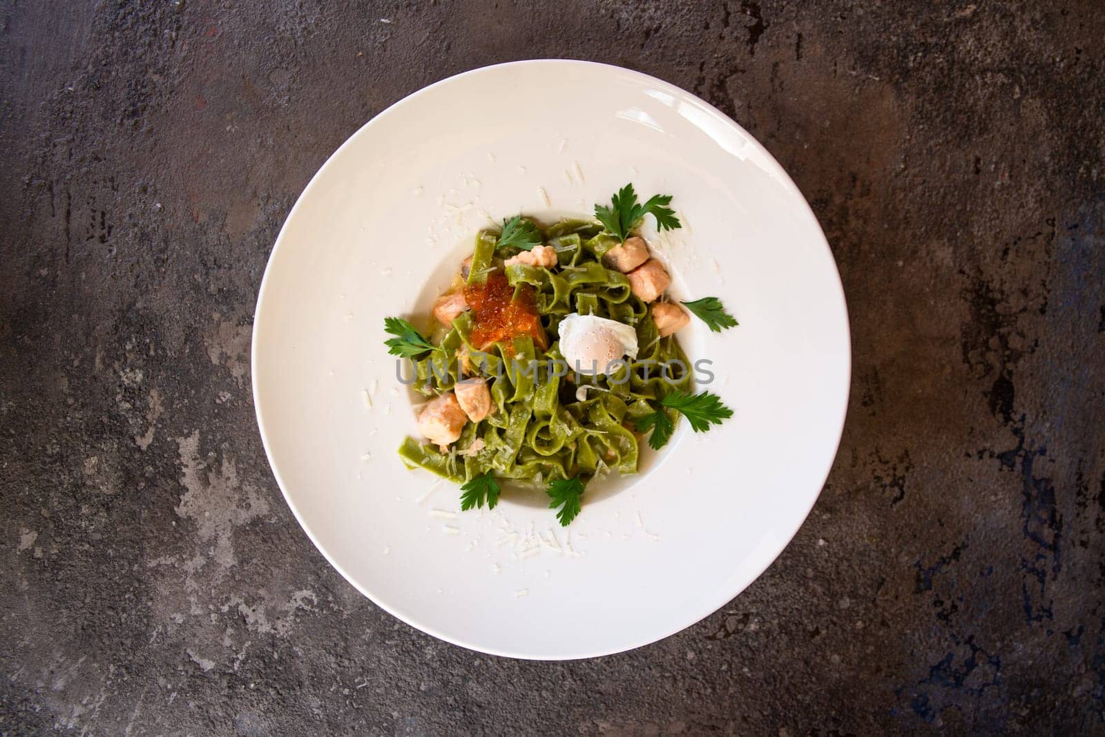 top view pasta with salmon and red caviar and greens in a white plate by Pukhovskiy