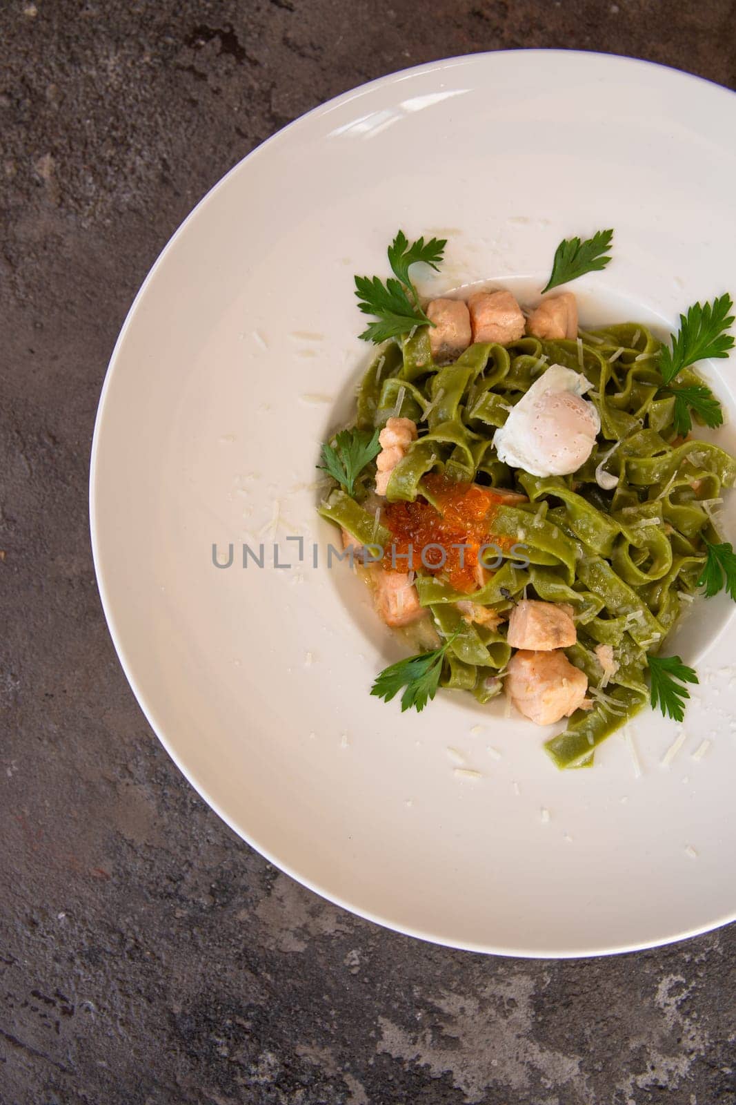 top view pasta with salmon and red caviar and greens in a white plate.