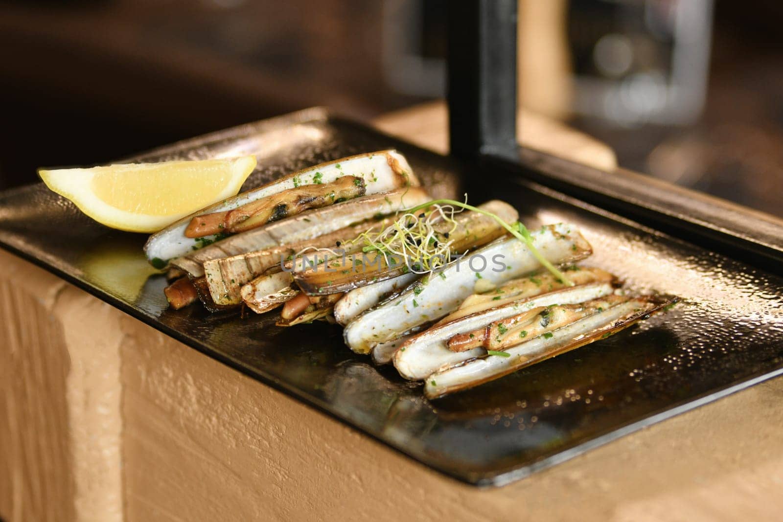 The shells knives, parsley and a lemon on black plate