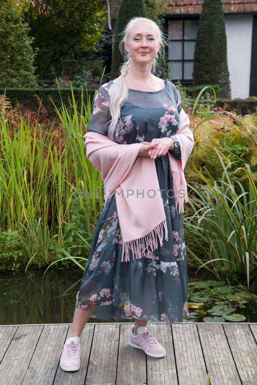 young beautiful woman in a long dress with a floral print and a pink shawl Fashionable style for spring and autumn demi-season clothing. High quality photo