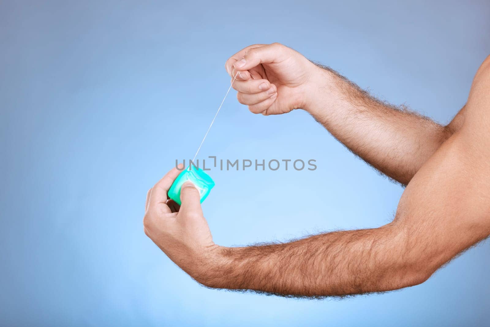 Floss, dental and man hands with container on studio mockup for teeth, mouth cleaning and marketing. Closeup of flossing product, thread and blue background for tooth cosmetics, mock up and backdrop.